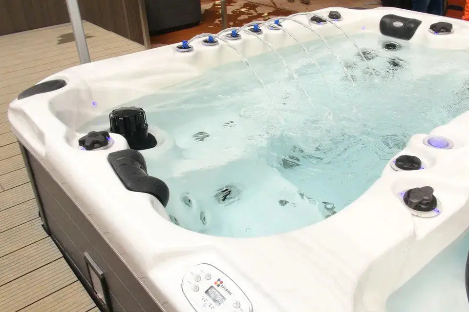 Witte zwemspa met meerdere jets en zwarte hoofdsteunen, jacuzzi buiten voor ontspanning.