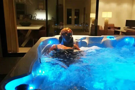 Luxe 5-persoons jacuzzi buiten met blauw verlicht zwemspa water en massagejets.